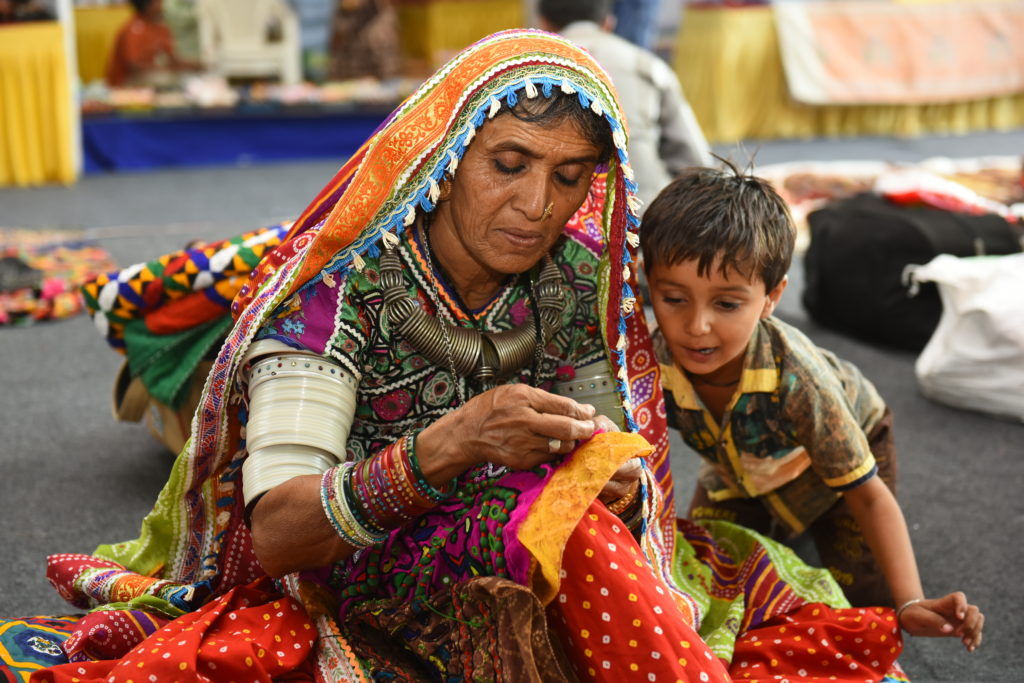 A women residing in interior Sindh, is sewing while her child is watching.